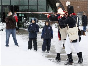 Aaron Gelb, front, of Haskins, Ohio, and Daniel Wilkens of Columbus, fire muskets today as Courtney Rivas-Hamp of Toledo, and her two sons Carlos, 8,  and Grant, 7, watch during the  200th anniversary of Fort Meigs in Perrysburg.