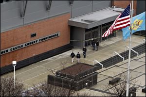 Law enforcement officials and investigators gather outside the New Castle County Courthouse in Wilmington, Del., Monday after three people died in a shooting at a courthouse.