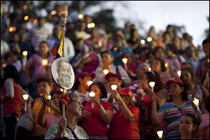 People hold up candles and images of Venezuela's President Hugo Chavez during candlelight vigil to pray for his health as he remains in a hospital undergoing cancer treatment, today in Caracas, Venezuela.