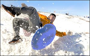 Miguel Sanchez, 16, flies off his sled as he goes off a ramp of snow today while sledding with friends in Garden City, Kan.
