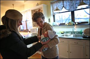 Family Resource Center social worker Leigh Pollworth hands baby Alex to Becky O'Connell at her home in Chicago. Mrs. O'Connell has served as a temporary foster mother for more than 70 infants over 10 years, taking care of them between the time their mothers placed them up for adoption until the adoptive parents take their baby home. 