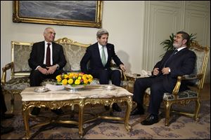 Egyptian Foreign Minister Mohammed Kamel Amr, left, U.S. Secretary of State John Kerry, center, and Egyptian President Mohamed Morsi take their seats at the starts of their meeting at the Presidential Palace in Cairo, Egypt today.