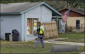 An engineer, tethered with a safety line, walks in front of a home where a sinkhole opened up underneath a bedroom late Thursday evening and swallowed a man in Seffner, Fla. on Saturday.