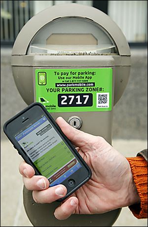 Downtown parking meters have stickers explaining how to pay the meter by phone. 