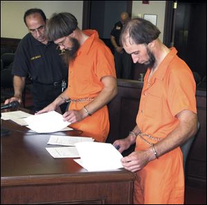 Jefferson County Sheriff Fred Abdalla, left, looks on as Lester Mullet, center, and his brother Johnny Mullet, right,  review papers during an extradition hearing at Jefferson County Common Pleas court during in Steubenville, Ohio.