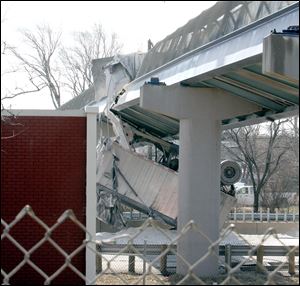 A dump truck is lodged underneath a pedestrian bridge over I-90 near E. 179 Street after its raised trailer struck the bridge, dumping its load and severely damaging the bridge today in Cleveland.