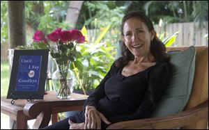 In this Dec. 31, 2012 photo, Susan Spencer-Wendel poses for photos with a copy of her book nearby, in her home in West Palm Beach, Fla. All the time-stamped rigors of daily journalism are behind her, but the pace of Spencer-Wendel's life has only been hastened. She is dying from Lou Gehrig's disease. What was once a constant rush to be first with her courthouse scoops has become a dash to live her remaining days joyfully, complete a long goodbye to those she loves, and record it all in a book that has drummed huge interest and a multimillion-dollar book deal. (AP Photo/J Pat Carter)