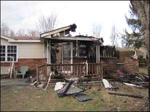 This photo shows the charred remains of  a home after a fire erupted, Saturday, in Gray, Ky.