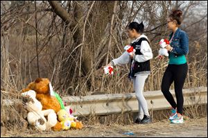 Dominique Ellison, left, and Rickie Bowling of Warren bring stuffed animals to a memorial in honor of their friends who died in a car crash Sunday on Park Avenue in Warren, Ohio.