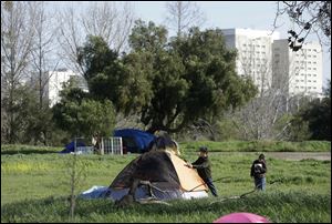 San Jose city workers Mark Ruffing, left, and Rita Tabaldo attach eviction notices to a tent at a tent city in San Jose. The Silicon Valley is adding jobs faster than it has in more than a decade as the tech industry roars back.But a more ominous record is also being set this year: food stamp participation just hit a 10 year high, African American wages fell 18 percent in two years and median incomes fell throughout the region. Simply put, while the ultra rich are getting even ultra richer, record numbers of Silicon Valley residents are slipping into poverty.