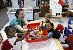 From bottom left, Serenity Johnson, 3, instructor Alisha Sligh, Owen Kruse, 3, and Taeler Gilmer, 3, play  at Toledo Day Nursery. The nonprofit nursery began in 1871 and has three sites in the city.