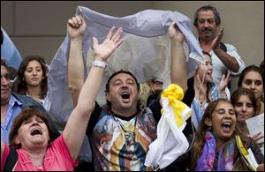 People hold an Argentine flag and sing outside the Metropolitan Cathedral to celebrate that the new pope is Jorge Bergoglio, Buenos Aires' former archbishop, today in Buenos Aires, Argentina.
