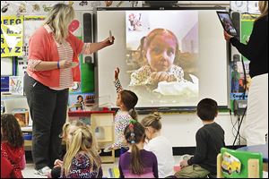 Preschool teacher Lori Brown, left, poses a question to Kyra Conrad, 4, who was using FaceTime to interact with her classmates Wednesday afternoon at Danbury Elementary in Marblehead. For two hours each day, Kyra uses an iPad to FaceTime with her class.