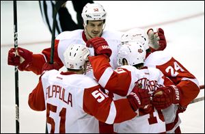 Detroit Red Wings' Jonathan Ericsson, clockwise from top, Damien Brunner, Henrik Zetterberg and Valtteri Filppula celebrate Zetterberg's goal against the Vancouver Canucks during the third period Saturday.