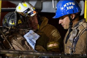 A worker, with black fire helmet at left, is rescued from an MTA subway construction project in New York early today after being trapped up to his chest in debris for several hours.