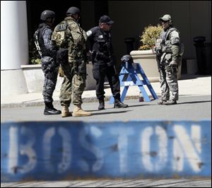 Officials in tactical gear stand guard behind a Boston Police Department barricade near the site of the Boston Marathon explosions, Wednesday, April 17, 2013, in Boston.