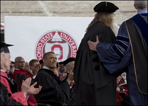 President Obama looks to famed photographer Annie Leibovitz, second from right, as she steps forward to receive an honorary doctorate during Ohio State University's spring commencement in the Ohio Stadium.