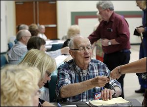 Election judge Bob Bachman checks in a voter at busy Bowling Green Church of the Nazarene.