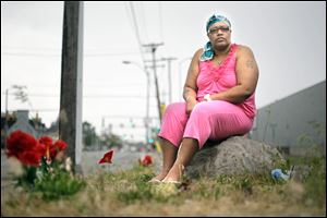 Jackie Chandler believes gang violence will grow.  She sits near flowers for La’Quan Dunbar, who was best friends with her nephew. Both men were shot to death. 