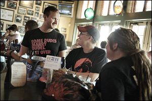 Lexi Staples, center, laughs while talking to Brent Rabie during Equality Toledo's Defense of Marriage Act decision party at Tony Packo's at the Park.  About 30 people gathered in the restaurant bar to celebrate the decision and support marriage equality.