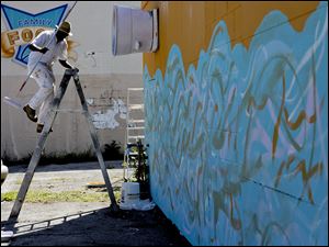 Artist Yusuf Lateef of Toledo works on a mural as part of the United Way’s Days of Caring at Dorr Street and Junction Avenue.