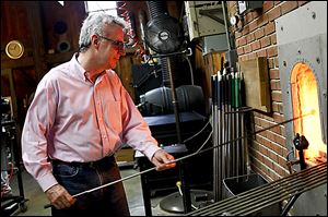 Glass artist Mark Matthews of Wauseon heats up glass in the furnace of the glass shop at Sauder Village in Archbold, Ohio..