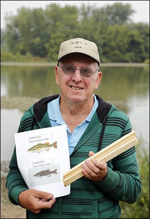 Perrysburg’s Joe Roecklein passes out measuring sticks and fliers so fisherman will know to release undersized bass. He said he often encounters anglers who keep the undersized fish.