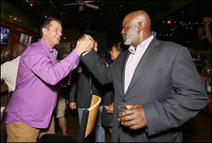 Mayor Mike Bell is greeted by Steve Cady at an election night party at Mulvaney’s Bunker Irish Pub in Toledo. Defeating Mr. Bell in the November election is the Democratic Party’s top goal. 