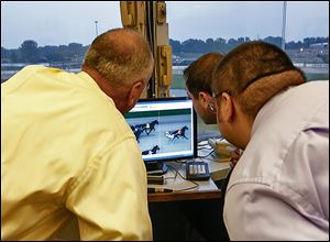 Bob Coberley, left, presiding judge of the State Racing Commission, and associate judges Zack Stommen, center, and Ryan Ratliff study the monitor in Race 4 and call a dead heat for place — second —on Raceway’s final night of live racing. 