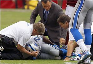 Detroit's Reggie Bush is attended to by training staff after injuring his knee Sunday against Arizona.