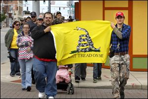 Jeremy Gensler, left, and Ryan Anderson lead members of Northwest Ohio Carry down Monroe Street during the group’s first open carry walk. 