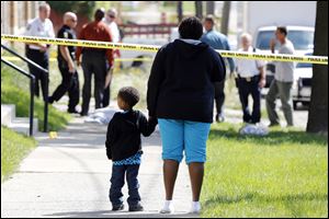 Deidra Hopings and her nephew Cross Hoffman, 3, watch as police investigate a shooting at 1520 Elm Street.