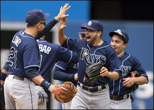 Tampa Bay Rays, from left, James Loney,  Matt Joyce, and Sam Fuld celebrate after beating the Blue Jays 7-6 on Sunday in Toronto.