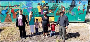 From left:  Yolanda Woodberry, Crystal Lanning, a resident of Moody Manor, Lanning's son Antonio Alvarez, 3, Bryonne Stenson, a resident of Moody Manor, Stenson's son Jeremiah Arnold, 4, and , Warren Woodberry, stand in front of a mural that the Woodberrys created at Moody Manor in a new garden. 
