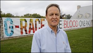 The Rev. Tony Scott poses near a sign promoting the G-Race campaign, which attempts to battle racism by affirming that the human race is one race.