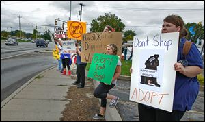 Protesters, including Lindsey Reed of Toledo, right, hold signs on Talmadge and Monroe as they demonstrate against the Family Puppy store that is coming to Westfield Franklin Park.