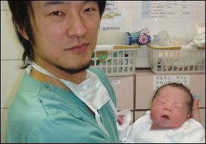 Dr. Kazuhiro Kawamura holds a newborn baby whose 30-year-old mother was treated for primary ovarian insufficiency, sometimes called premature menopause.