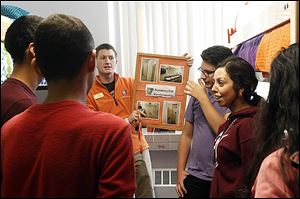 Student volunteer Mike Reilly talks about residential life and holds a picture of the dorm restroom and shower facilities in Kohl Hall to Latino students considering attending BGSU.