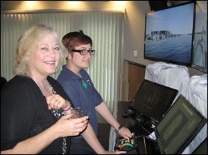 Harbor View Yacht Club member, Katherine LaGrange watches Maritime Academy of Toledo cadet, Alexis Knapp, on the demonstration maritime simulator.