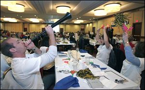 William Adamiak blows the vuvuzela as his NAMSA teammates, including Jennifer Shafer, second from right, and Kelly Jobe, cheer during The Blade Corporate and Community Spelling Bee. 