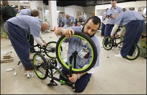 In December, 2012, Yousser Ramadan, center, and other inmates assemble bicycles for children served by Lucas County Children Services. The Toledo prison offers inmates a chance to take on community service projects.