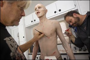 Kevin Galbraith, 24 of Marietta, Ga., undergoes a three-hour make-up session to transform into his zombie character with the help of effects make-up artists Andy Schoneberg, right, and Kevin Wasner, left, on the set of AMC's television show, “The Walking Dead,” in Senoia, Ga.