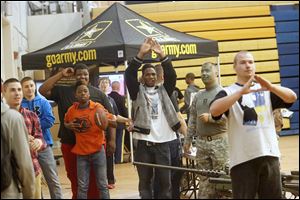 Students call for balls as Fred Willis, 14, center left, gets lined up to take his shot at an Army target during a hand-eye coordination exercise in the Whitmer High field house in Toledo. 
