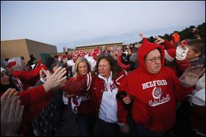 Mary, center, and Mark Durbin, right, lead the football team down a tunnel created by students and community members as they take the field before the start of Bedford's game against Monroe Jefferson on Friday.