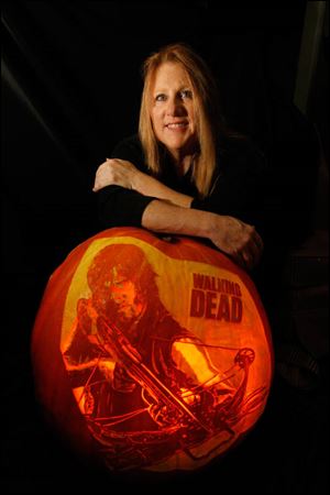 Jackie Koepfer and her Walking Dead pumpkin, featuring character Daryl Dixon.  Koepfer carves pumpkins in her Swanton, Ohio living room.