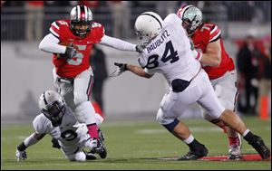 Ohio State quarterback Braxton Miller, top left, escapes the grasp of Penn State cornerback Jordan Lucas, bottom left, as Ohio State offensive lineman Corey Linsley, right, blocks Penn State defensive tackle Kyle Baublitz during the first quarter.
