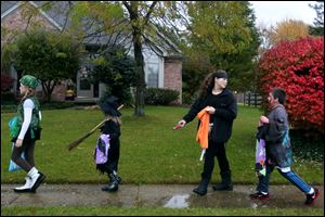 Paige Kamer, 10, left, Kylie Pakulski, 6, center left, Payton Kamer, 12, center right, and Mitchell Pakulski, 9, all of West Toledo, raced from house to house while trick-or-treating in Bedford on Halloween.