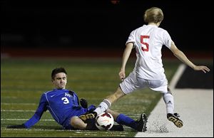 Anthony Wayne's Jared Russell slides to move the ball against  Mentor's Alan Wardeiner in Wednesday's match.