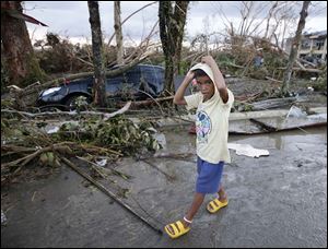 A boy walks past deva-stated homes and toppled trees from Typhoon Haiyan in the Philippines’ Leyte province Saturday.  