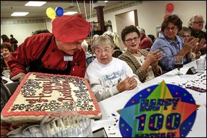 Chef Marshall Goldstein, left, presents a homemade birthday cake to Franciscan Sister Juliana Sienko during the celebration of her 100th birthday at the Rosary Care Center in Sylvania. 